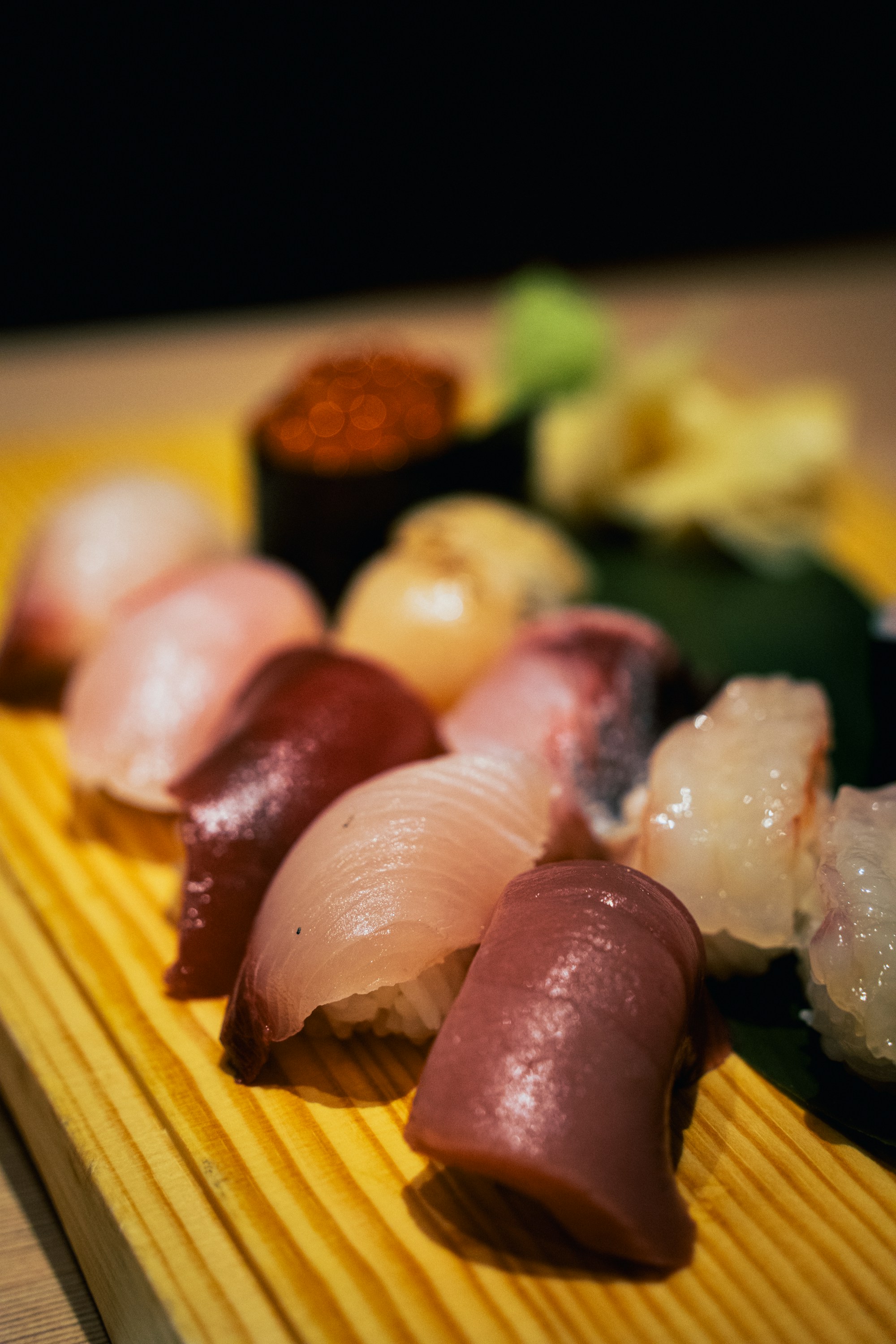 Peças de sushi sobre tábua de madeira clara em luz baixa